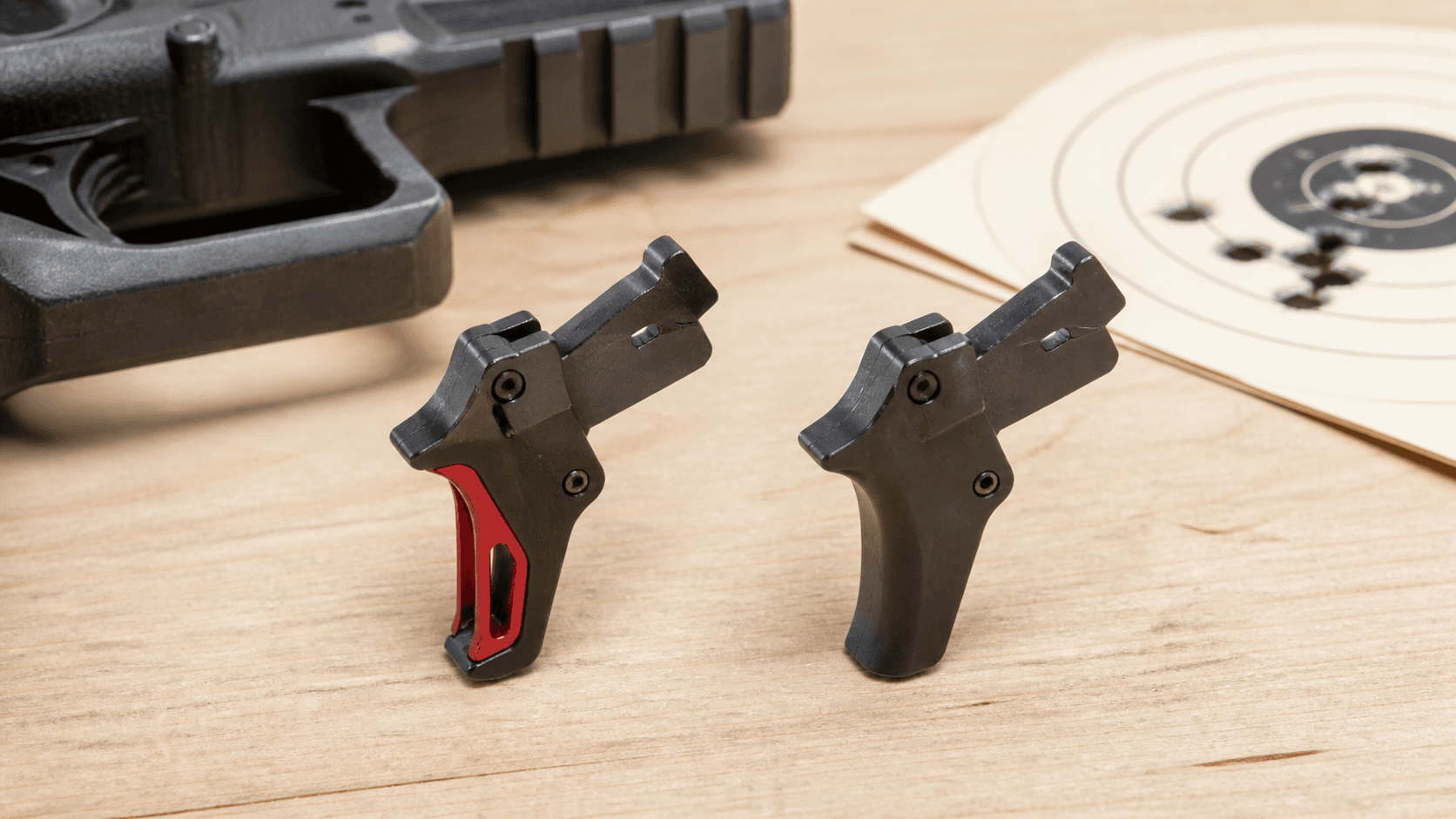 Close-up of a black pistol trigger against a blurred indoor shooting range backdrop.